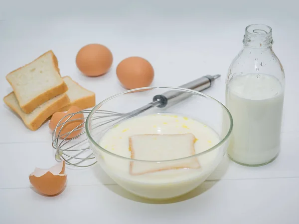 Un pedazo de pan de trigo en la mezcla leche-huevo para la preparación de pan francés . — Foto de Stock