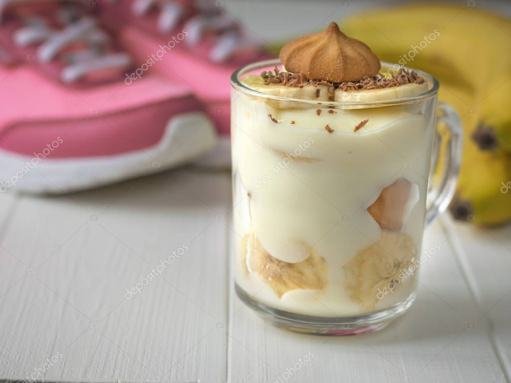 Bananen-Pudding in Glas Becher mit Keksen und Sneakers im Hintergrund ...