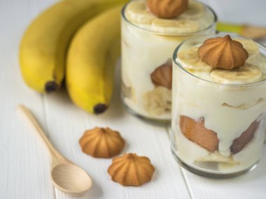 Gözlüklü bir beyaz tahta vintage masada kurabiye ile muz puding.