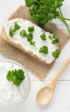 Kavramsal görüntü taze krem peynir Beyaz ahşap masa üzerinde otlar ile.