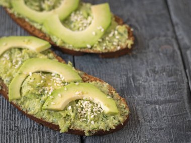 İki dilim ekmek buğday unu üzerinden avokado yeşil otlar ile krema ile bulaşmış. Bir vejetaryen diyet.