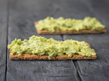 Taze gevrek ekmek krem ve avokado bir rustik ahşap siyah tablo ile.