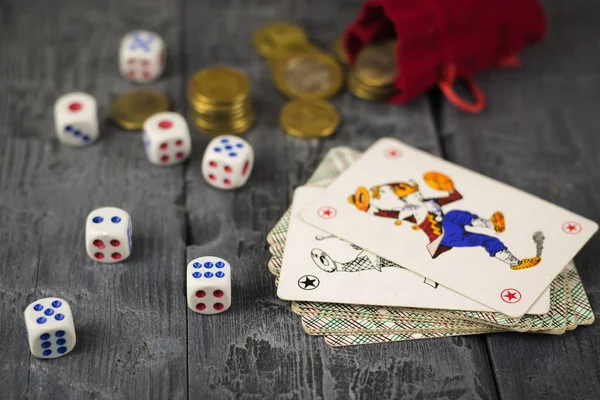 Dice, coins and cards Joker on a wooden game table.