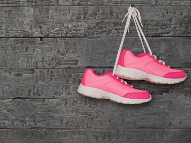 Çift pembe Bayan koşu ayakkabıları tarafından dantel ahşap duvarda asılı.