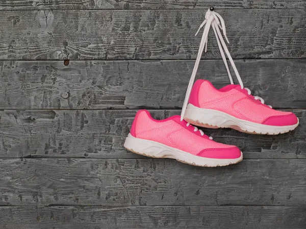 Çift pembe Bayan koşu ayakkabıları tarafından dantel ahşap duvarda asılı.