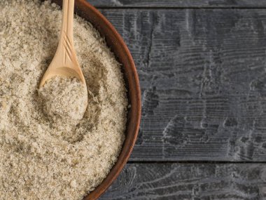 Kase otlar ve hafif ahşap masanın üzerine bir yemek kaşığı tuz dolu. Üstten Görünüm.