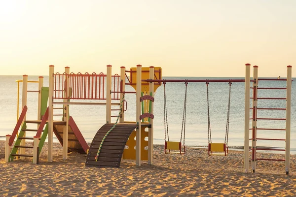 Çocuk sahilde slayt ile renkli salıncaklar.