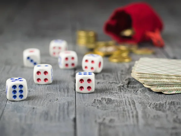 Münzen aus einer Tüte und rote Würfel auf einem Holztisch. — Stockfoto