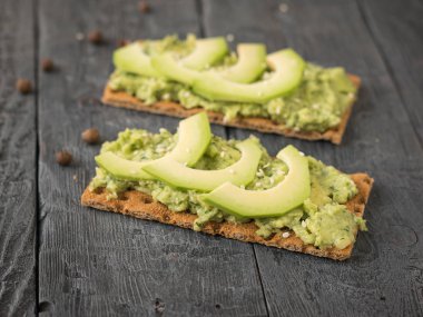 Çıtır çıtır ekmek buğday unu krem ve masanın üzerinde avokado dilimleri ile gelen.