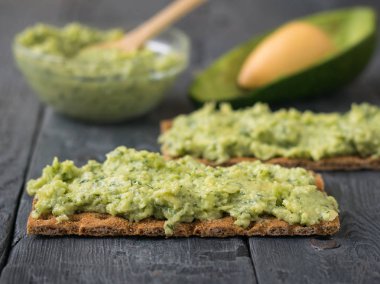 Pate avokado ahşap bir masa üzerinde bir gevrek ekmek üzerinde.