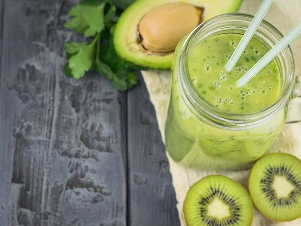 En nygjord smoothie med avokado, banan, apelsin, citron och kiwi på ett träbord. Kost vegetarianmat. Råa livsmedel. — Stockfoto