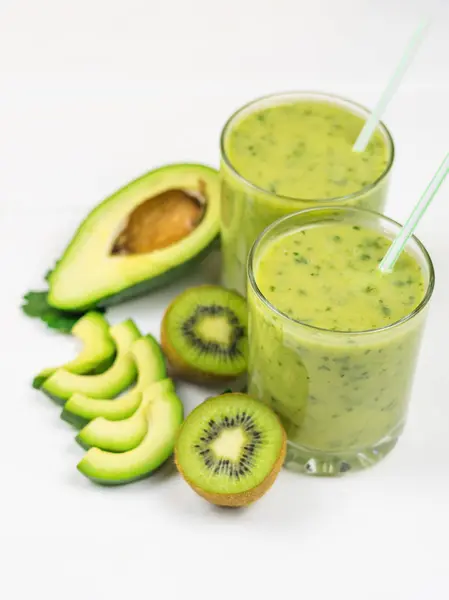 A freshly prepared smoothie of avocado, banana, orange, lemon and kiwi on a white table. Diet vegetarian food. Raw foods. — Stock Photo, Image