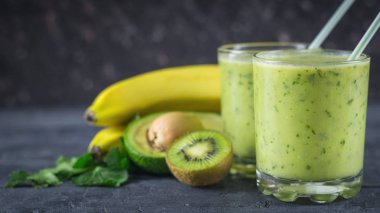 Smoothies avokado, muz, kivi ve ahşap bir masa üzerinde otlar dan. Diyet vejetaryen yemek.
