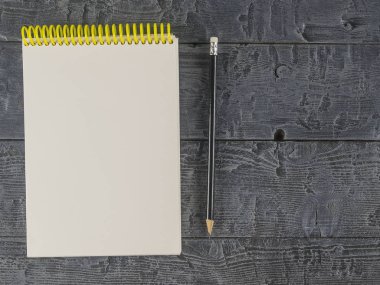 Not defteri ve koyu ahşap bir masa üzerinde siyah kalem. Üstten Görünüm.