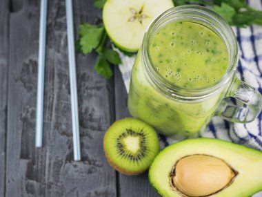 Taze avokado otlar ve iki kokteyl kamış ile smoothies ahşap bir masa üzerinde yapılmış. Diyet vejetaryen yemek.