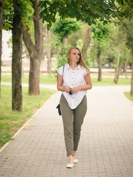 Mujer con gafas en las manos caminando por el Parque mirando hacia arriba . — Foto de Stock