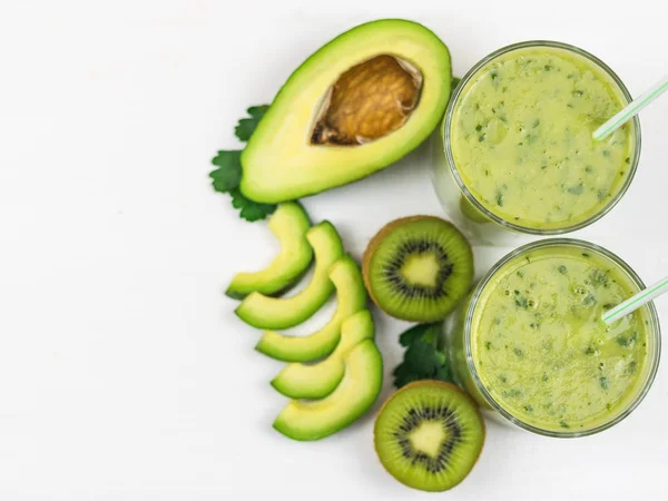 En nygjord smoothie med avokado, banan, persilja, citron och kiwi på en vit träbord. Kost vegetarianmat. Råa livsmedel. — Stockfoto