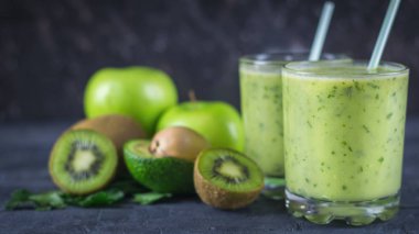 Smoothies avokado, muz, kivi ve koyu ahşap bir masa üzerinde otlar dan. Diyet vejetaryen yemek.
