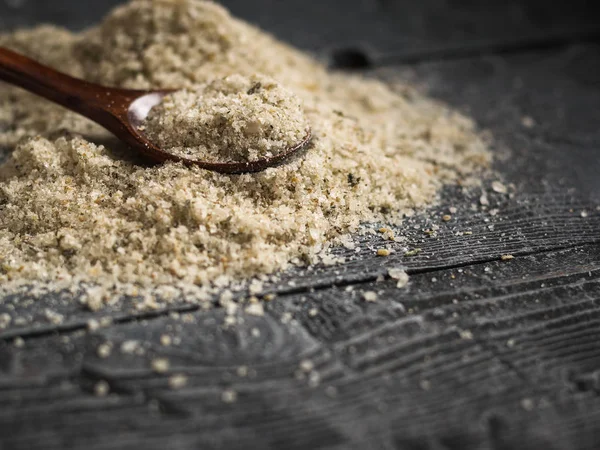 Una gran pila de sal con hierbas con una cuchara de madera sobre una mesa vintage negra . — Foto de Stock