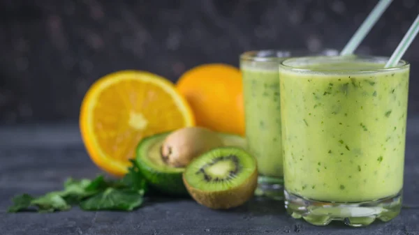 Två glas fyllda med smoothie avokado på en svart träbord med frukter. Kost vegetarianmat. — Stockfoto