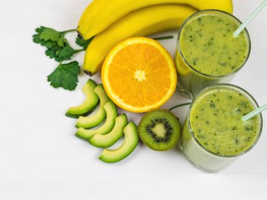 Taze hazırlanmış bir yüzlü, avokado, muz, maydanoz, limon ve kivi Beyaz ahşap bir masa üzerinde. Diyet vejetaryen yemekleri. Çiğ gıdalar. Detoks.