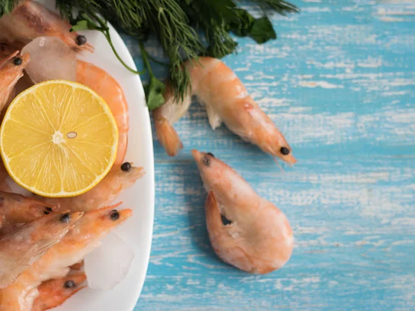 Udang beku dalam mangkuk putih gerabah dengan lemon dan dill di atas meja kayu . — Stok Foto