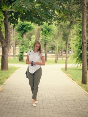 Güzel bir kadının Beyaz gömlekli parkta yürüyüş.