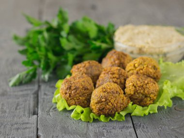 Koyu ahşap bir masa Tahin soslu marul üzerinde taze pişmiş falafel yaprak.