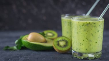 Smoothies avokado, kivi ve otlar bir siyah ahşap karanlık tablo. Sağlıklı bir yaşam tarzı için Vejetaryen yiyecekler.