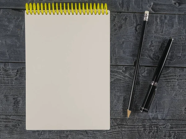 Zwart vulpen en potlood met een notitieblok openen op zwarte houten tafel. Het uitzicht vanaf de top. — Stockfoto