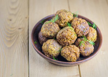Taze otlar ahşap bir masa üzerinde bir kil kase falafel yaptı.