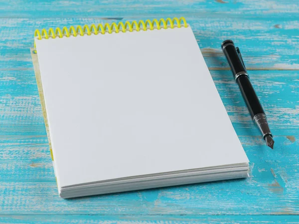 Opende notebook met een vulpen op een blauwe houten tafel. Het uitzicht vanaf de top. — Stockfoto