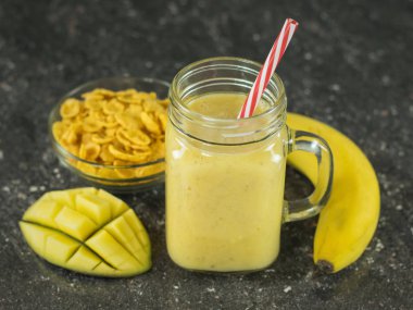 Taze mango, muz, portakal ve tahıl ile smoothies yaptı.