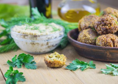 Taze pişmiş kil kase tahin sosu ile ahşap bir masa üzerinde falafel.