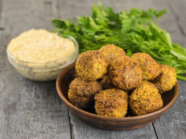 Taze pişmiş kil kase tahin sosu ile ahşap bir masa üzerinde falafel. Rustik tarzı.