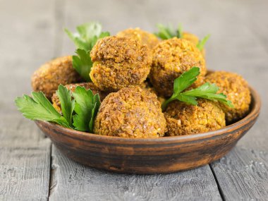 Taze otlar koyu ahşap bir masa üzerinde bir kil kase falafel yaptı.