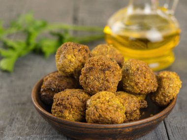 Taze pişmiş kil kase tahin sosu ve yağ ile ahşap bir masa üzerinde falafel.