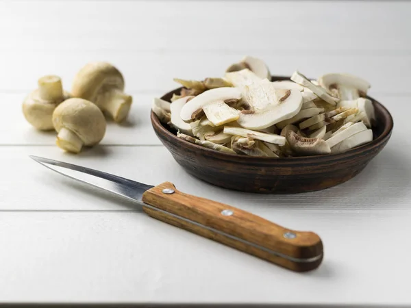 Свежие нарезанные грибы в глиняной чаше на белом деревянном столе . — стоковое фото
