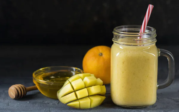 A smoothie of mango, banana, honey and cereal on a black background. — Stock Photo, Image