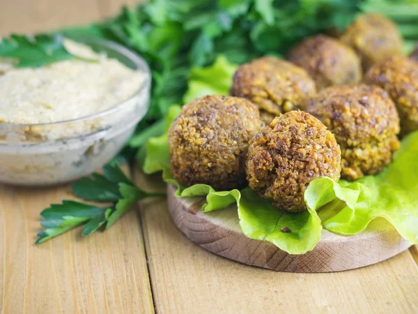 Taze sos Tahin ve maydanoz ve dereotu ile bir kesme tahtası üzerinde falafel yaptı.