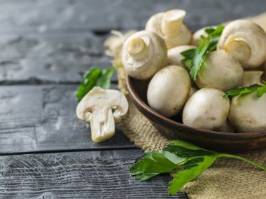 Taze mantar bir kil kase ve maydanoz koyu bir rustik ahşap tablo. Vejetaryen yiyecekler tablodur.