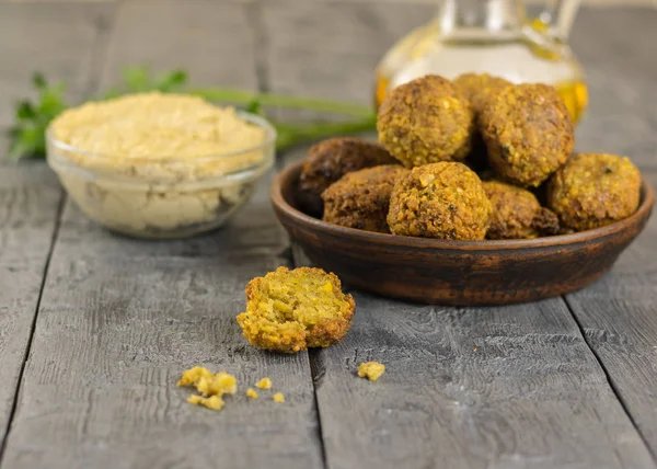 Freshly cooked falafel on clay bowl on a wooden table with tahini sauce and parsley. — Stock Photo, Image