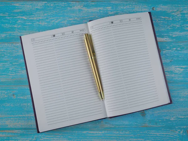 Geopende notebook met een gouden pen op een tafel. Het uitzicht vanaf de top. — Stockfoto