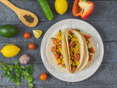 Üç Meksikalı taco yemek pişirmek için malzemelerle bir plaka üzerinde.