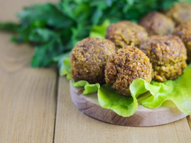 Taze bir salata yaprağı bir kesme tahtası üzerinde falafel yapılmış klasik.