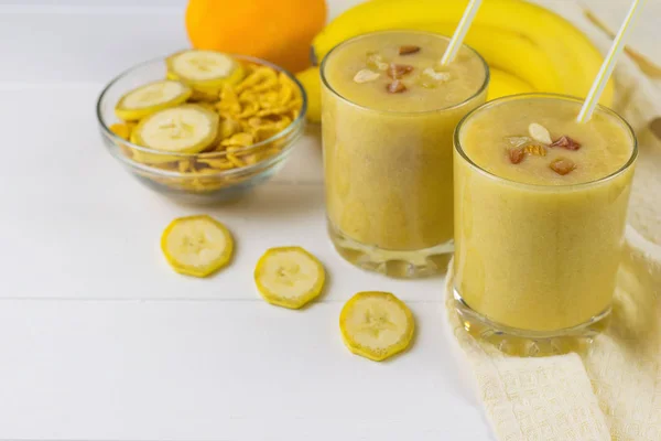Smoothie yang baru dibuat dengan mangga, pisang, jeruk, madu dan sereal di atas meja kayu putih . — Stok Foto
