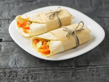 Buğday unu bir masada beyaz kase gelen iki sebze rulo tortilla.