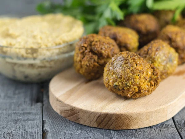 Pasta Tahina in einer Glasschüssel und Falafel auf einem Schneidebrett auf einem Holztisch. — Stockfoto