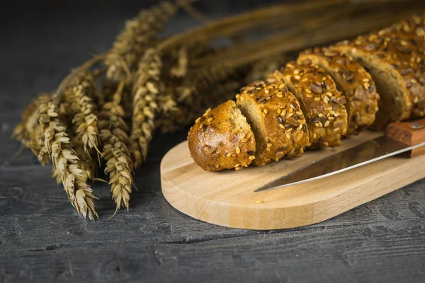 Baguete fatiada é marrom dourado na tábua de corte na mesa de madeira . — Fotografia de Stock