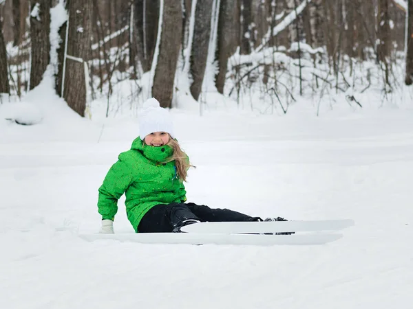Flickan i grön färg föll när ridning på skidor. — Stockfoto